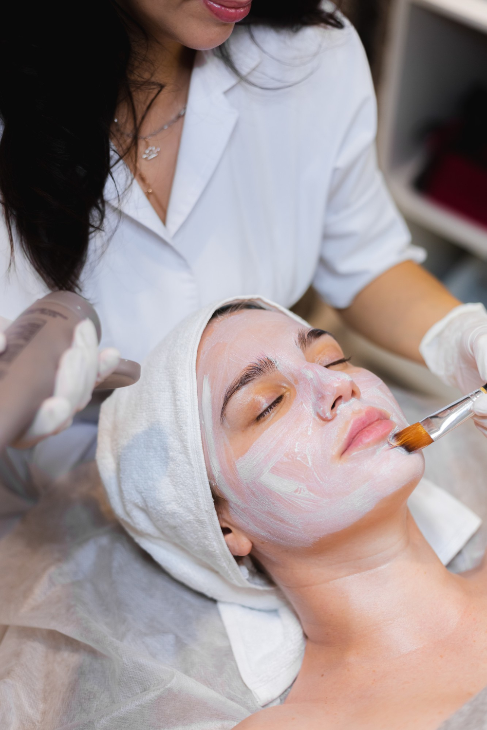 beautician-with-brush-applies-white-moisturizing-mask-face-young-girl-client-spa-beauty-salon